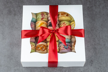 Gift box of colorful macarons. A white gift box filled with colorful assorted macarons tied with a bright red ribbon