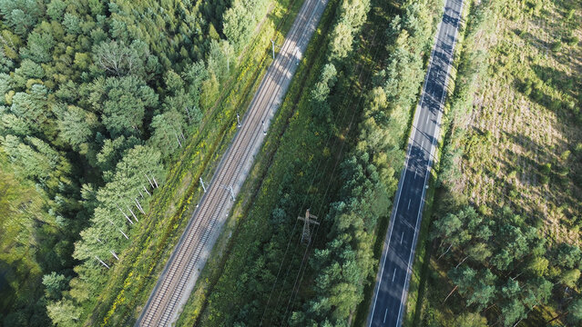 Overhead view of railway and road through a green forest