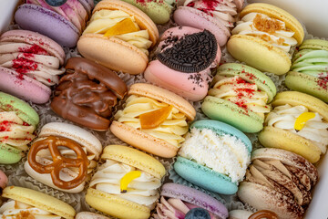 Sweet macarons in gift box. A gifting box filled with assorted sweet macarons decorated with creams and toppings