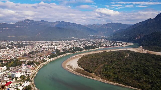 A bird's-eye view of Rishikesh City in Uttarakhand surrounded by lush green hills on a cloudy day. It is a hilly Indian town located along the Ganges River. Beautiful Indian city.