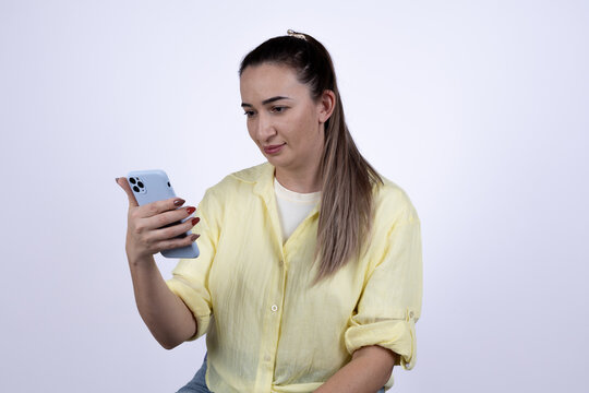The woman is looking at her smartphone with a focused expression