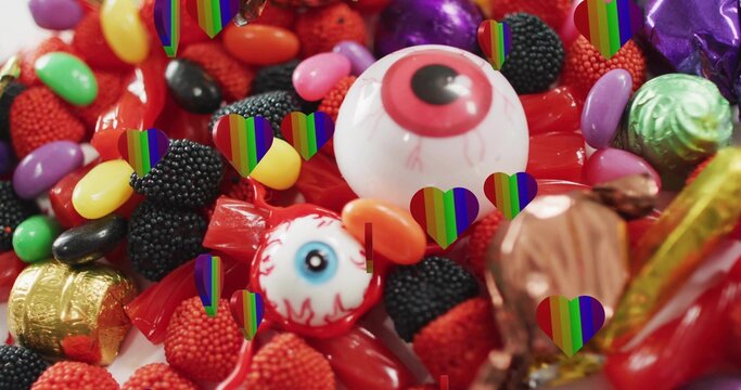 Naklejki Featuring large white eyeball gumball on white table with wrapped eyeball candies rainbow overlays
