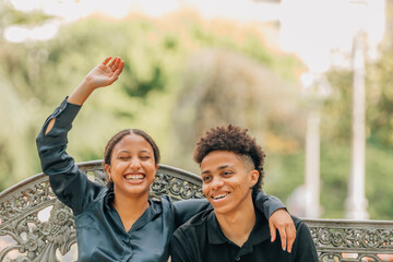happy young couple smiling on a bench outdoors