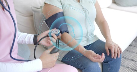 Measuring pink-scrub nurse applying BP cuff to patient in mint blouse at home, with overlay