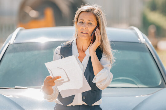 woman with phone and car calling insurance company and assistance