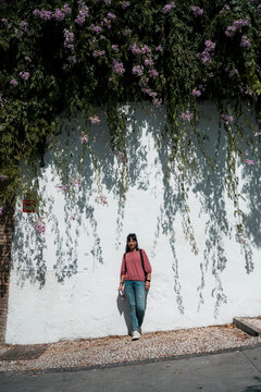 Woman under purple flowers against white Andalusian wall