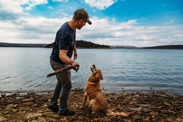 Man and dog playing fetch at lake