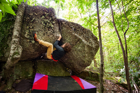 A climber fights his way up an off width crack on a boulder