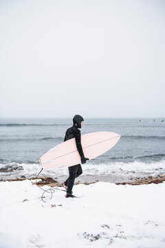 Solo Woman with surfboard going to surf in the snow