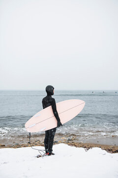 Solo Woman with surfboard going to surf in the snow