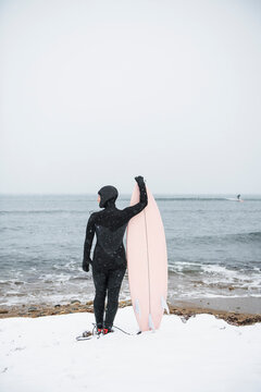 Solo Woman with surfboard going to surf in the snow