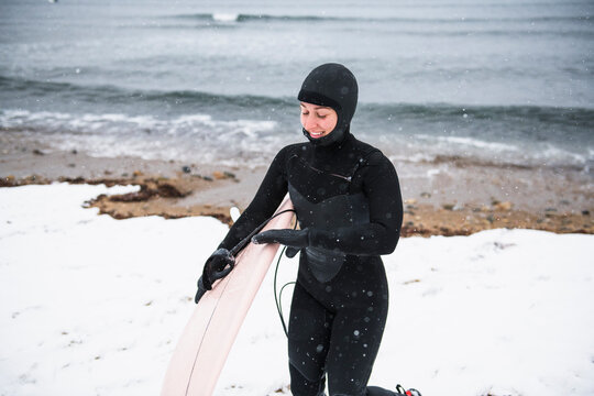 Solo Woman with surfboard going to surf in the snow