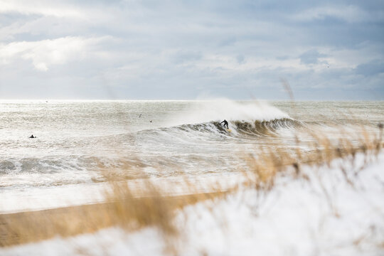 Man surfing winter waves during snow storm