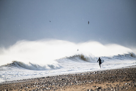 Man going surfing winter waves during snow storm