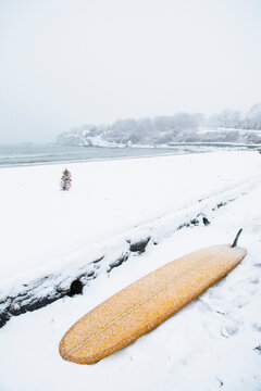 Surfboard at the beach during snowstorm