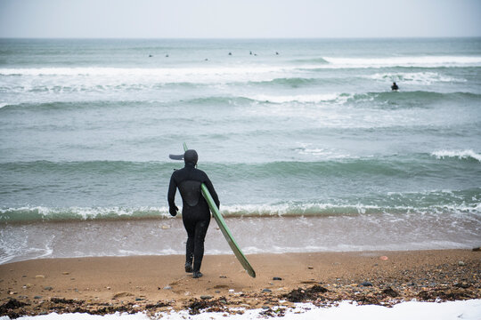 Woman with surfboard on a snowy beach