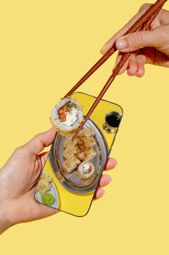 Sushi roll reflected in a phone on a bright background