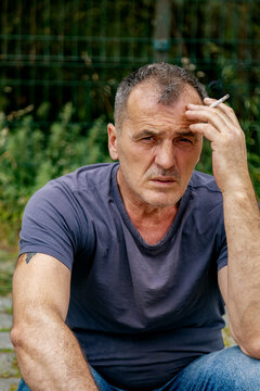 Portrait of sad smoking man sitting outdoors