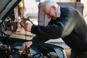 Elderly man repairing a car engine in a workshop
