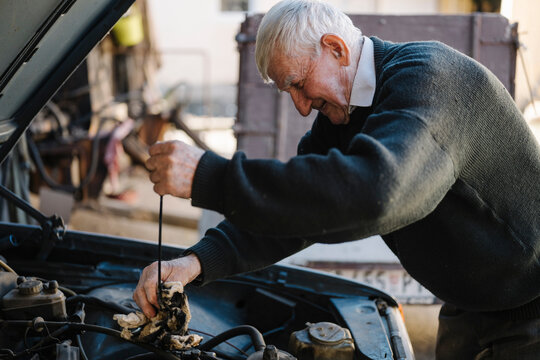 Elderly man repairing a car engine in a workshop