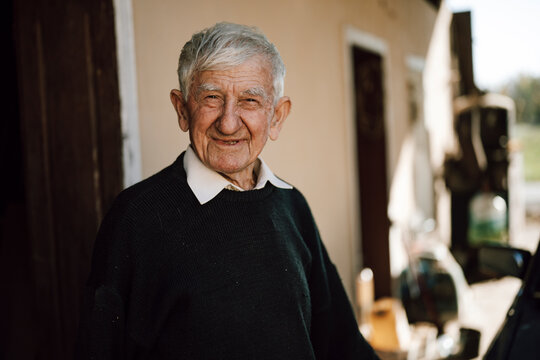 Elderly man smiling warmly stands in doorway