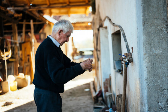 Elderly man tending to a water faucet