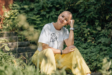 Authentic outdoor portrait of bald woman on steps among leafy green