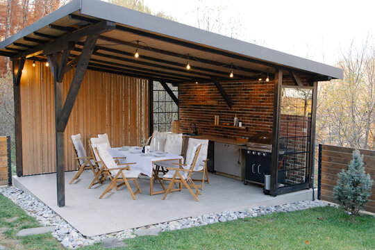 Outdoor kitchen and dining area under modern gazebo structure