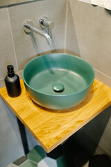 Modern bathroom sink on wooden countertop with green bowl