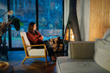 Woman relaxing in a cozy cabin by the fireplace