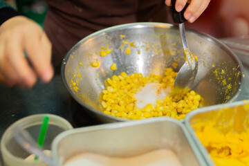 Close up hand of street vendor during cooking for mixed corn butter, sweet and simply Thai dessert