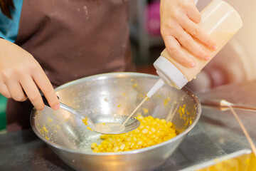 Selective focus of corn mix with butter, milk and sugar in a metal bowl for sweet buttery milk corn...