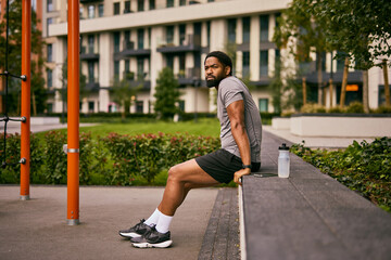 Man Seated On Park Bench Contemplating Weight Loss Journey And Fitness Goals Outdoors