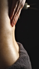 A close-up of a massage therapist's hand applying pressure to a client's back, highlighting relaxation and wellness in a serene spa setting. The focus on the hand and skin texture conveys calm.