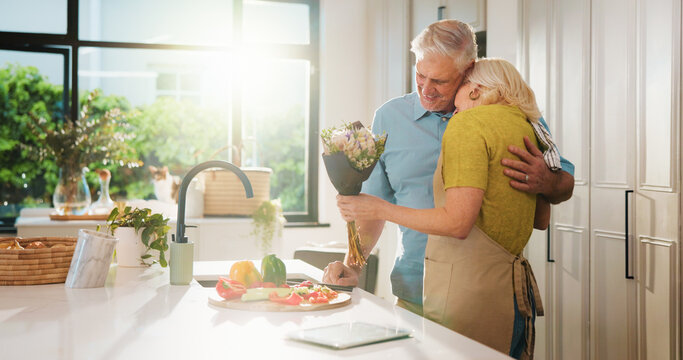 Hug, flowers and cooking with old couple in kitchen of home for anniversary celebration, romance and gift. Love, present and bouquet with senior man and woman in house for date and meal prep - Powered by Adobe