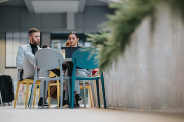 A team of professionals sit around a table at a modern cafe, engaging with a laptop and discussing ideas in a relaxed, collaborative setting.