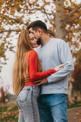 Fototapeta premium Couple sharing tender moment amidst colorful autumn leaves scene
