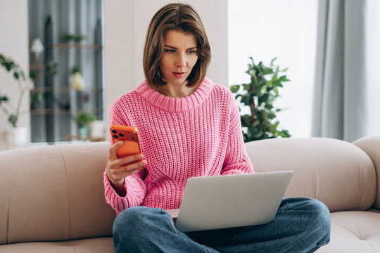 Woman working from home multitasking with laptop and smartphone