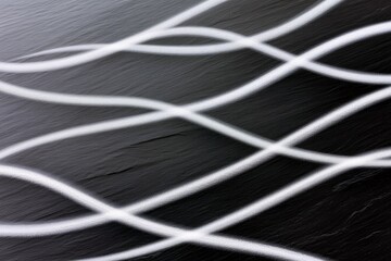 A dark, textured surface is overlaid with flowing, white, wavy lines that intersect and create a dynamic, abstract pattern.