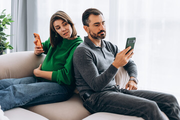 Pregnant woman looking at man's phone showing jealousy