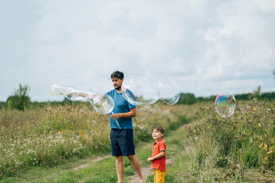 Father and son playing together with soap bubbles in field
