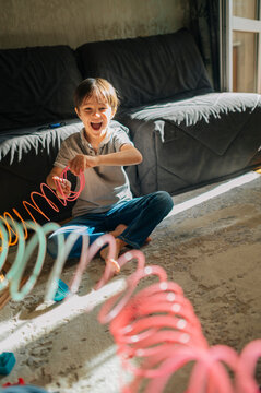 Boy playing with a colorful spring toy at home in the living room