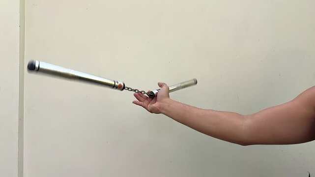 Close up a hand doing nunchaku swing , white background , slow motion video.