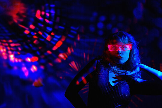 Person wearing VR glasses dancing in neon-lit nightclub with cyberspace theme