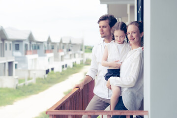 A loving couple and their child stand together on a balcony, gazing at a developing residential area. This picture evokes feelings of aspiration, family values, and planning for the future.