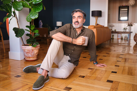 Relaxed man enjoying coffee and optimism in a sunny living room