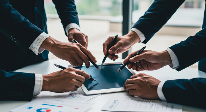 Focused hands around a digital tablet, symbolizing the dynamic environment of a boardroom setting. Capturing the essence of teamwork and data-driven decision-making.