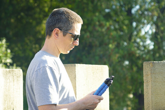 Person holding a compact tripod after a filming session in a park. Concepts of successful content creation, travel photography satisfaction, portable gear convenience, and DIY mobile video production.