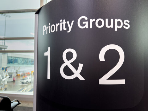 An airport departure gate sign welcomes passengers in boarding groups 1 and 2