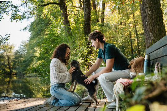 Couple enjoying time with dog outdoors in nature by a lake